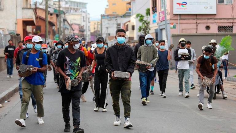 Protesters carry stones to erect a barricade during an anti-government protest in Ankadifotsy, Antananarivo, on October 1, 2025. - Mamyrael / AFP