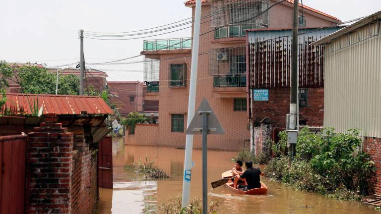 A man paddles in a boat with a boy as they make their way through floodwater after days of heavy rainfall, at a village in Qingyuan, Guangdong province, China August 8, 2025. Florence Lo/ REUTERS