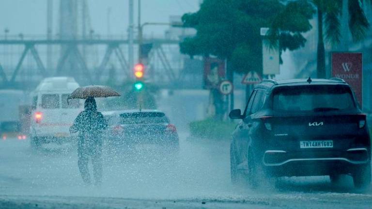 People commute along a street amid heavy rains ahead of a cyclonic storm in Chennai - AFPpix