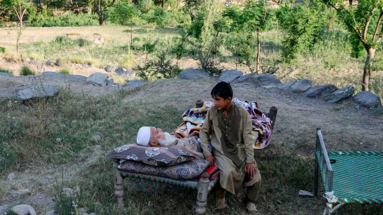 Seorang budak lelaki duduk di sebelah datuknya di atas katil di luar rumah mereka, susulan gempa bumi dahsyat di kampung Bambakot, daerah Dera Noor, wilayah Nangarhar, Afghanistan, 6 September 2025. REUTERS/Sayed Hassib