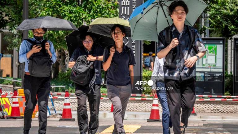 People shield themselves from the hot sun with umbrellas in Tokyo on August 27, 2025. Tokyo experienced a record 10 consecutive days of temperatures 35C or above, the weather office said on August 27. - Yuichi YAMAZAKI / AFP
