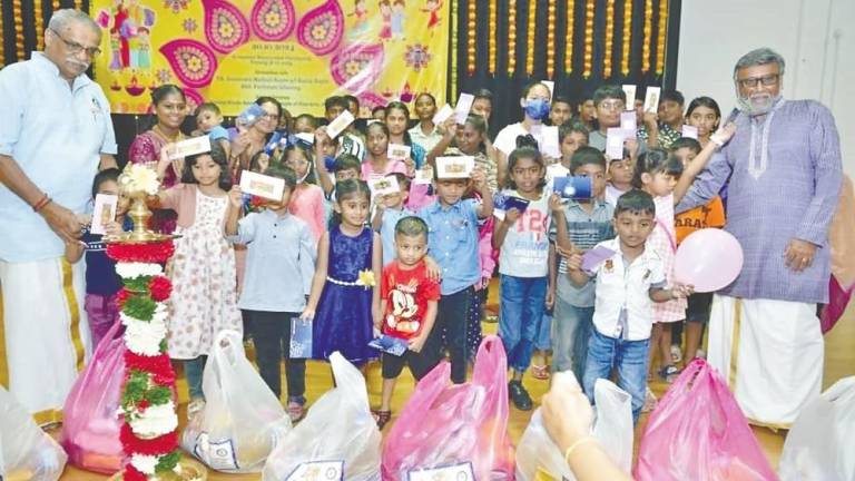 Murugiah (left) and PHA committee member K. Ganesan (right) with children and parents during the event. – Pix courtesy of Penang Hindu Association