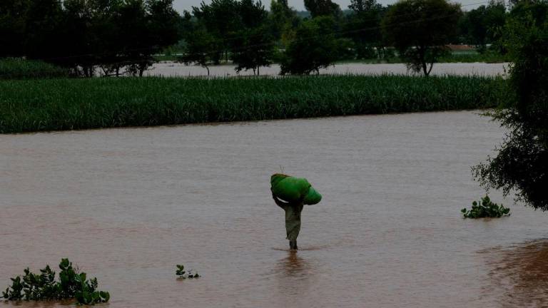 A man carries a sack of fodder on his head as he walks along a flooded road, following monsoon rains and rising water levels of the Chenab River, in Patraki village, Chiniot district, Punjab province, Pakistan, August 30, 2025. REUTERS/Akhtar Soomro