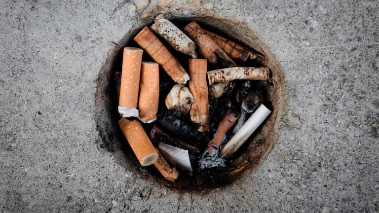 This photograph shows cigarette butts in a makeshift ashtray in a cement block, in Paris, on June 27, 2025. - JOEL SAGET / AFP