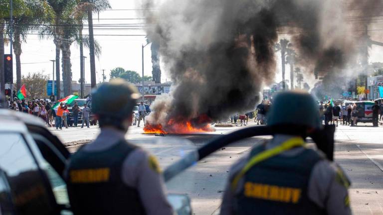 A car burns as law enforcement clashes with demonstrators during a protest following federal immigration operations, in the Compton neighborhood of Los Angeles, California on June 7, 2025. AFP