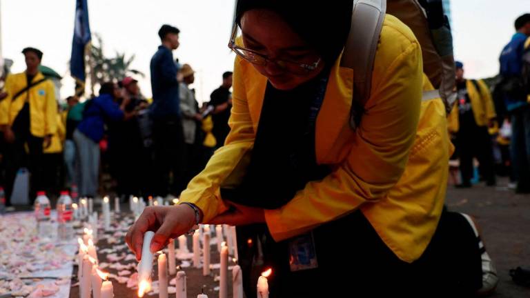 A university student lights candles to offer condolences for victims who were killed during widespread protests over parliamentarians’ extra pay and housing allowances, during a protest demanding the release of detained demonstrators, outside Indonesian parliament building in Jakarta, Indonesia September 4, 2025. REUTERS/Willy Kurniawan