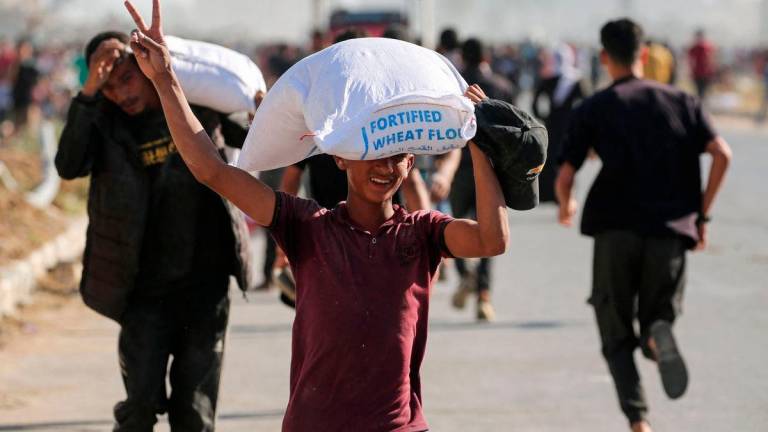 Displaced Palestinians ferry bags of food aid after storming a World Food Programme warehouse in Deir el-Balah in the central Gaza Strip on May 28, 2025 AFPpix