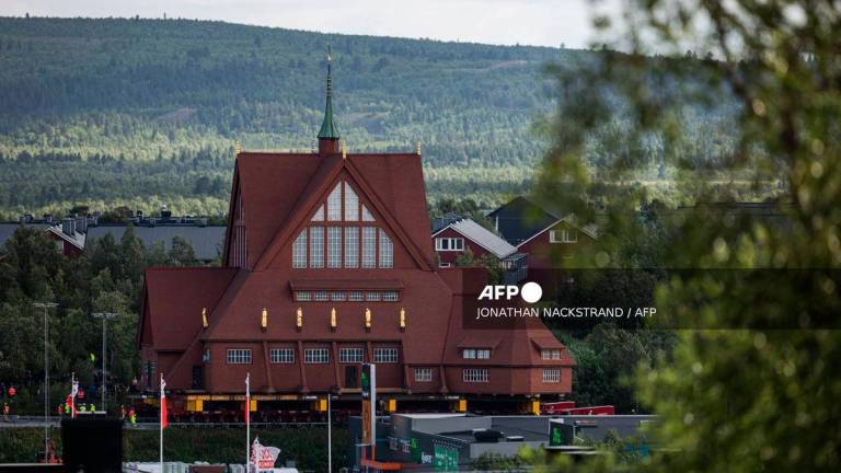 The wooden Kiruna Church is seen in the background as it is being transferred to its new location, in Kiruna, Sweden on August 19, 2025. (Photo by Jonathan NACKSTRAND / AFP)