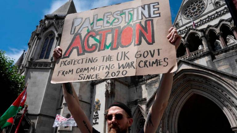A supporter of pro-Palestinian campaign organization Palestine Action holds a banner outside London’s High Court in London, Britain - REUTERSPix