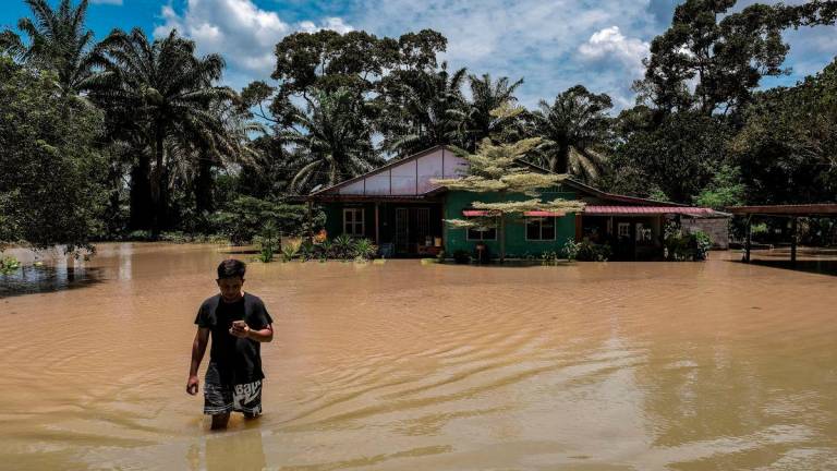 Seorang penduduk, Muhammad Riduan Jamil berjalan keluar dari rumahnya yang dinaiki air ketika tinjauan fotoBernama di Kampung Paya Embun, Pekan Nenas di sini hari ini -fotoBERNAMA