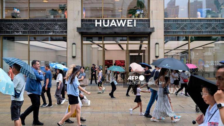 For representational purposes only: People walk past the Huawei Shanghai flagship store in the Huangpu district in Shanghai, on June 23, 2025. (Photo by Hector RETAMAL / AFP)
