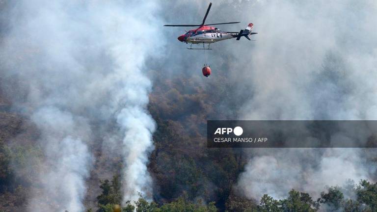 A firefighter helicopter flies above a wildfire in Garano, near Leon, northwestern Spain, on August 25, 2025. - Cesar MANSO / AFP
