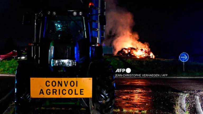 A tractor near a fire on a roundabout during a demonstration dubbed “Feux de la colere” (Fires of Wrath) called by French farmers’ union - (Photo by Jean-Christophe VERHAEGEN / AFP)