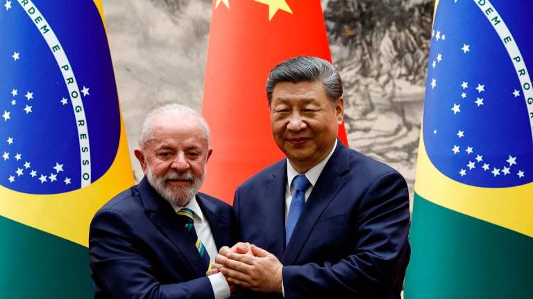 (FILES) Chinese President Xi Jinping (R) shakes hands with Brazil’s President Luiz Inacio Lula da Silva. - TINGSHU WANG / POOL / AFP