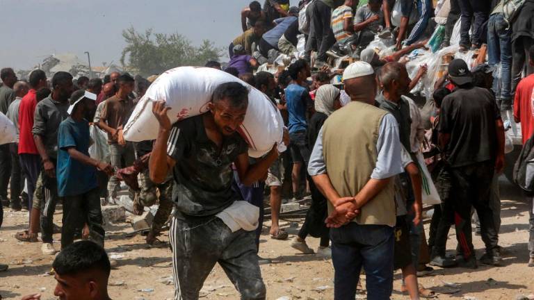 A man carries a bag of food as displaced Palestinians raid trucks carrying humanitarian aid in Khan Yunis, in the southern Gaza Strip on August 9, 2025. - AFPpix