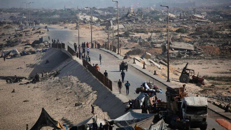 Palestinians walk on a coastal path northwest of Nuseirat refugee camp as they are displaced southward following an Israeli announcement of closing Al-Rashid road towards the north of the besieged Gaza Strip on October 4, 2025. (Photo by Eyad BABA / AFP)