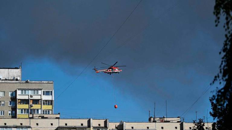 A firefighter helicopter flies as rescuers work at a site of a heavily damaged residential building following Russian drone and missile strikes in Kyiv on September 7, 2025, amid the Russian invasion of Ukraine. Russia fired its biggest-ever aerial barrage at Ukraine early on September 7, setting the seat of the Ukrainian government in Kyiv ablaze, authorities said.