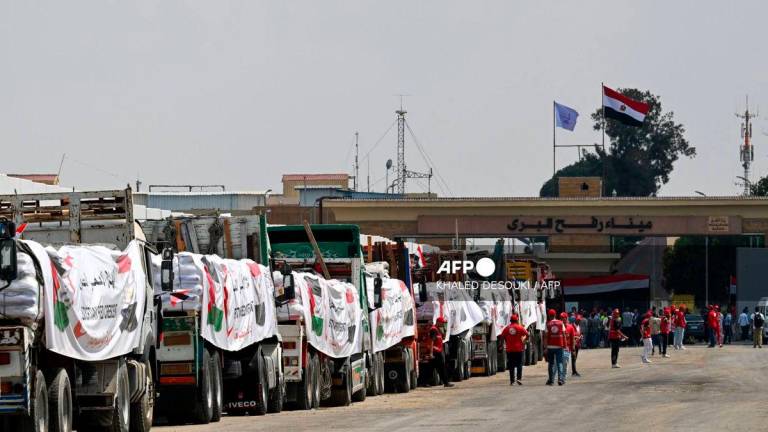 People walk past trucks loaded with aid for Gaza, waiting on the Egyptian side of the Rafah crossing in Rafah on August 18, 2025. AFPPix