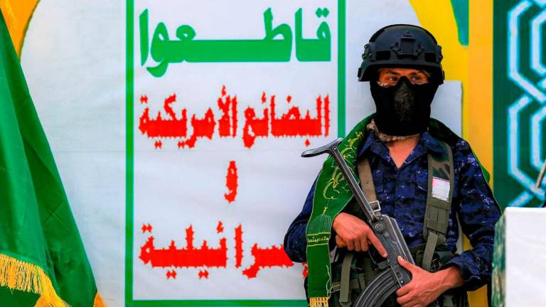 For representational purposes only: A member of security forces loyal to Yemen’s Huthis stands guard by banner depicting their slogan urging a boycott of all US and Israeli goods, during an event at Sanaa University on the eve of the birthday of Islam’s Prophet Mohamed, in Sanaa on September 3, 2025. (Photo by Mohammed HUWAIS / AFP)
