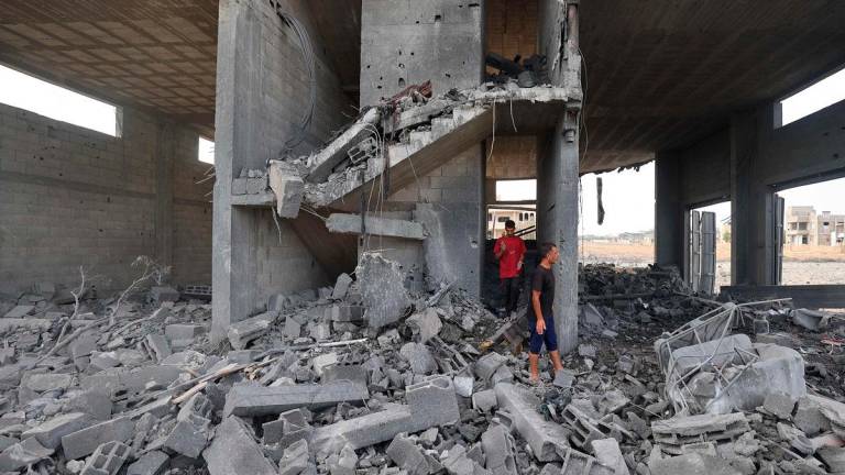 Palestinians walk amid the rubble of a building hit in an Israeli strike in the Bureij refugee camp in the central Gaza Strip on July 10, 2025. - Eyad BABA / AFP