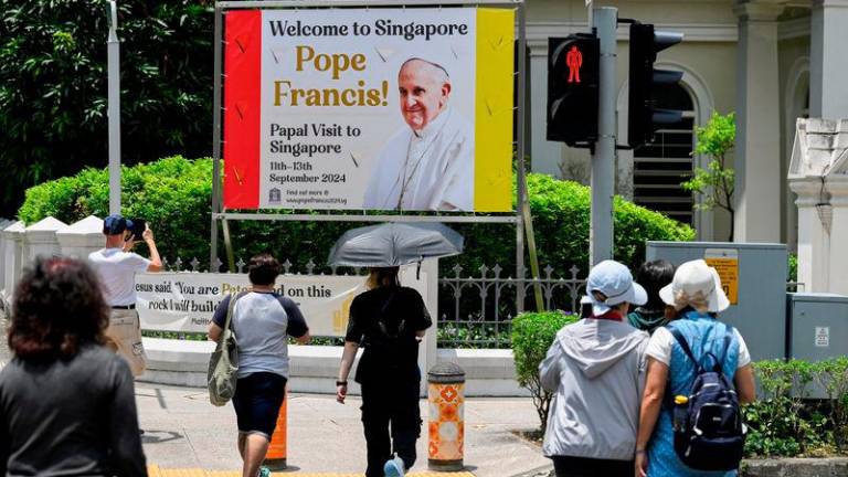 People walk past a poster of Pope Francis, ahead of his visit to Singapore, at the Cathedral of the Good Shepherd, Singapore, September 11, 2024.REUTERSPIX