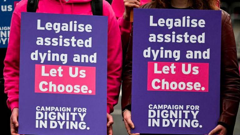 Campaigners from Dignity in Dying hold a placard during a demonstration outside The Palace of Westminster, home to the Houses of Parliament in central London, on October 16, 2024, during a gathering in favour of the proposal to legalise euthanasia in the UK. - AFPPIX