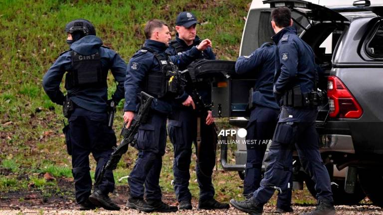 Heavily armed police gather at a staging point during a search for a fugitive linked to the murder of two police officers, in Porepunkah on August 29, 2025. Australian police said on August 28, that they will not rest until they catch a 56-year-old gunman who fled into the bush two days earlier after allegedly killing two officers. Detectives said they were speaking to the man’s partner and searching rugged, forested terrain near the small town of Porepunkah, in the northeast of Victoria state. (Photo by William WEST / AFP)