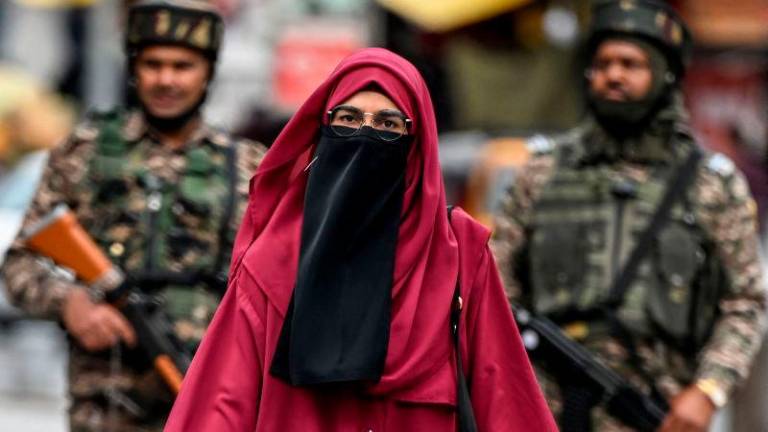 A Kashmiri woman walks at a marketplace as Indian paramilitary soldiers stand guard in Srinagar on May 3, 2025. AFPpix
