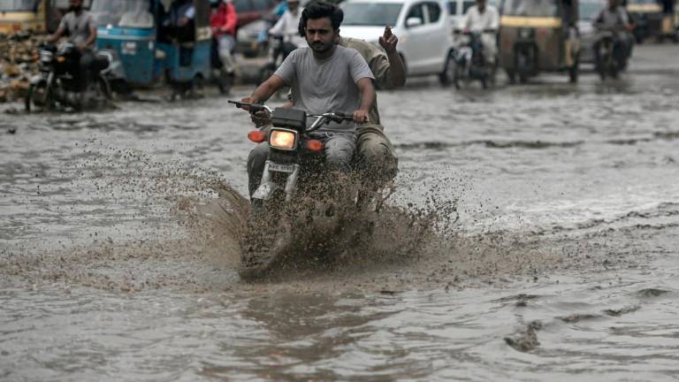 Commuters make their way through a flooded street after heavy rainfall in Karachi on June 28, 2025. - Rizwan TABASSUM / AFP