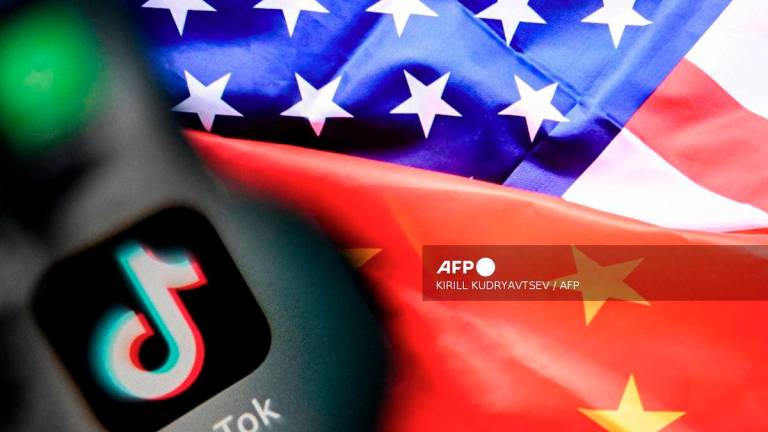 (FILES) A photo taken on April 10, 2025 shows the Chinese social networking service TikTok's logo on a smartphone screen (L) and US and China flags combo illustration on a laptop screen in Frankfurt am Main, western Germany. - AFP