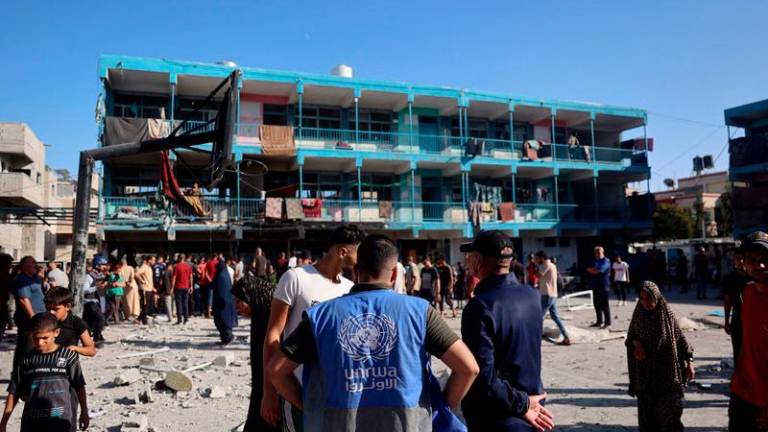 A member of the United Nations Relief and Works Agency for Palestine Refugees (UNRWA) checks the courtyard of a school after an Israeli air strike hit the site, in Nuseirat in the central Gaza Strip on September 11, 2024, amid the ongoing war in the Palestinian territory between Israel and Hamas. An Israeli air strike on September 11 hit a central Gaza school, with the Hamas-run territory's civil defence agency reporting 10 killed in the facility turned displacement shelter and the military saying it had targeted militants. - Eyad BABA / AFP