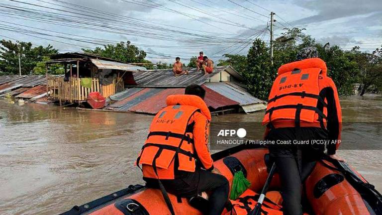 This handout photo taken on September 26, 2025 and released on September 27 by the Philippine Coast Guard shows coast guard personnel rescuing residents from their flooded house at the height of Severe Tropical Storm Bualoi, at a village in Ormoc City, Leyte province- AFP PHOTO / PHILIPPINE COAST GUARD