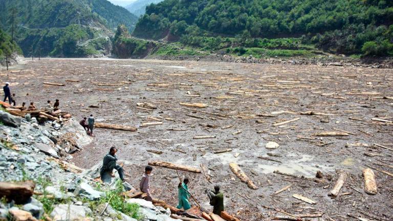 Locals collect woods from Noseri Dam near Muzaffarabad, the capital of Pakistan-administered Kashmir, on August 16, 2025, a day after flash floods. Rescuers were struggling to retrieve bodies from debris after flash floods triggered by heavy monsoon rains across northern Pakistan killed at least 344 people in the past 48 hours, authorities said on August 16. Photo by Sajjad QAYYUM / AFP