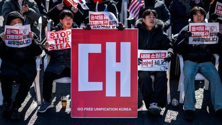 Demonstrators sit beside a board that reads Go Free Unification Korea (C) during a rally in support of impeached South Korea president Yoon Suk Yeol in the Gwanghwamun area of Seoul on January 4, 2025. South Korea's political leadership was in uncharted territory January 4 after the sitting president resisted arrest over a failed martial law decree days before the warrant expires. (Photo by Philip FONG / AFP)