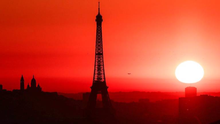 The sun rises by the Eiffel Tower and the Sacre Coeur Basilica ontop of the Montmartre hill in Paris on July 1, 2025, as the city is on red alert for high temperatures, with the top of the Eiffel Tower shut, polluting traffic banned and speed restrictions in place as a searing heatwave gripped Europe. - AFPpix