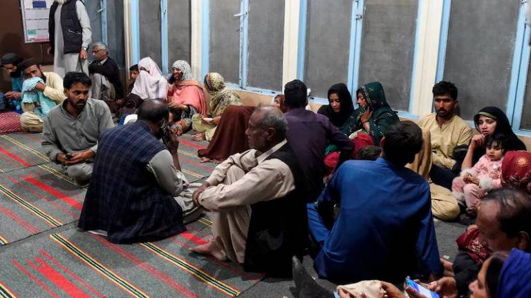 Passengers, who were rescued from a train after it was attacked by separatist militants, sit at the Mach Railway Station in Mach, Balochistan - REUTERSpix