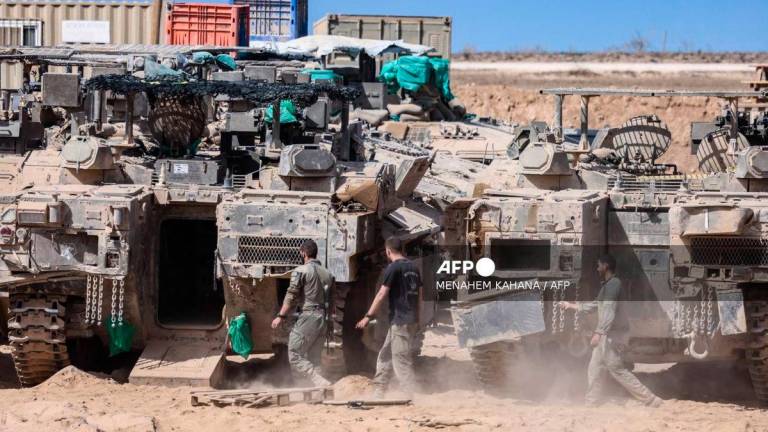 Israeli soldiers carry out maintenance on tanks positioned in southern Israel, on the border with the Gaza Strip on October 11, 2025. - AFP