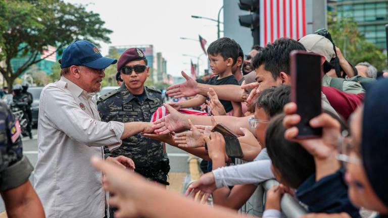 Perdana Menteri Datuk Seri Anwar Ibrahim menyantuni orang ramai pada perbarisan Sambutan Hari Kebangsaan 2025 di Dataran Putrajaya hari ini - fotoBERNAMA
