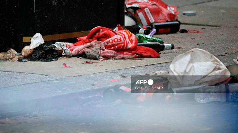 Discarded Liverpool scarves and flags lay in the road behind a police cordon on Water Street in Liverpool, north-west England on May 27, 2025, after a car ploughed in to crowds gathered to watch an open-top bus victory parade for Liverpool's Premier League trophy parade on May 26. - AFP