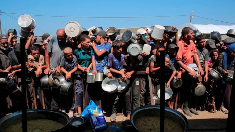 Palestinians wait to receive food portions from a charity kitchen in Khan Yunis in the southern Gaza Strip on August 27, 2025. (Photo by AFP)