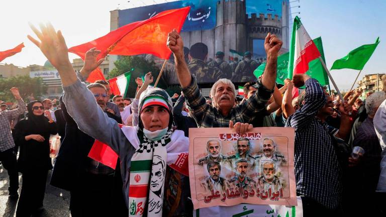 Iranians lift flags and placards during a rally protesting the US attack on Iran in Enghelab Square in Tehran on June 22, 2025. Iran’s President Masoud Pezeshkian condemned US strikes on nuclear sites on June 22, saying in his first response that the attack revealed Washington was “behind” Israel’s military campaign in the Islamic republic. - ATTA KENARE / AFP