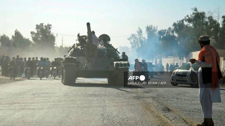 Taliban security personnel on a Soviet-era tank are followed by motorcyclists as they ride towards the border, during ongoing clashes between Taliban security personnel and Pakistani border forces, in the Spin Boldak district of Kandahar Province on October 15, 2025. - Sanaullah SEIAM / AFP