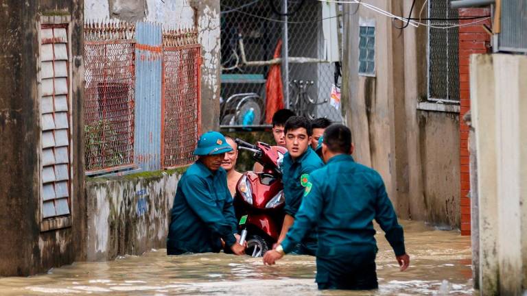 Paramilitary officers carry a motorcycle from a flooded area after Typhoon Bualoi made landfall in Nghe An province, Vietnam. - REUTERS/Thinh Nguyen