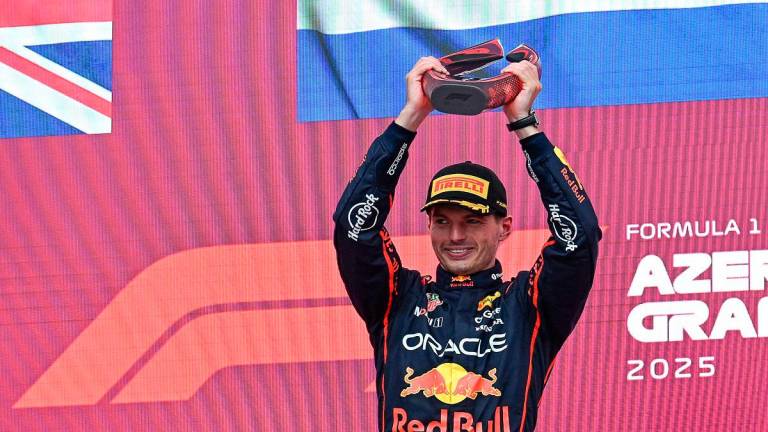 Red Bull Racing’s Dutch driver Max Verstappen celebrates with his trophy on the podium after the Formula One Azerbaijan Grand Prix at the Baku City Circuit in Baku on September 21, 2025. - Ozan KOSE / AFP