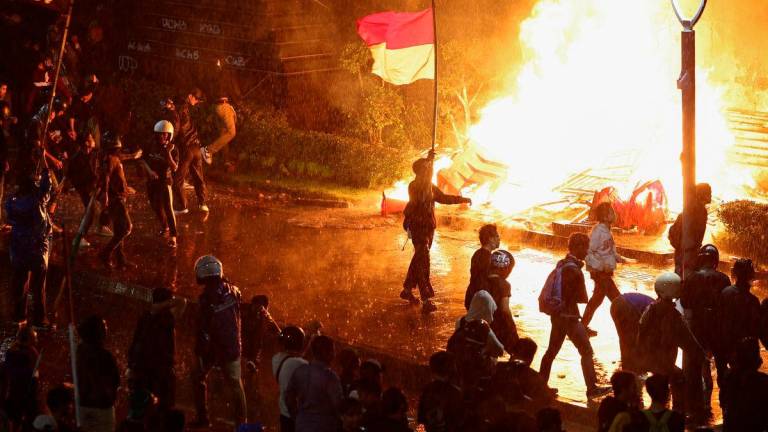 Protesters carry an Indonesian flag and a flag from Japanese anime ‘One Piece’ during a protest outside Jakarta police headquarters, after a motorcycle taxi driver died after being struck and run over by a police tactical vehicle during Thursday’s protest on a number of issues, including parliamentarians’ allowances, education funding and the government’s school meals programme, in Jakarta, Indonesia, August 29, 2025. REUTERS/Willy Kurniawan