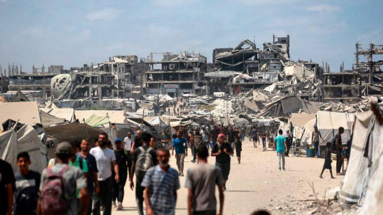 Palestinians walk along a street near war-damaged buildings in Gaza City on August 8, 2025. Israel’s military will “take control” of Gaza City under a plan proposed by Prime Minister Benjamin Netanyahu and approved by his security cabinet, triggered a wave of criticism from across the world. Photo by Bashar TALEB / AFP