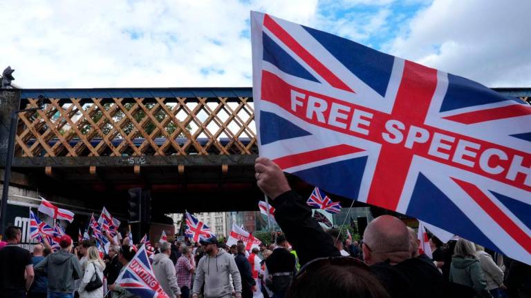 Supporters of British far-right activist Tommy Robinson whose real name is Stephen Yaxley-Lennon, walk through central London waving flags during a ‘Free speech’ march, on September 13, 2025. (Photo by CARLOS JASSO / AFP)