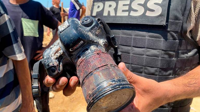A journalist holds a blood-covered camera belonging to Palestinian photojournalist Hussam al-Masri, a Reuters contractor who was killed in an Israeli strike on Nasser hospital in Khan Yunis in the southern Gaza Strip, during his funeral on August 25, 2025. - AFPpix