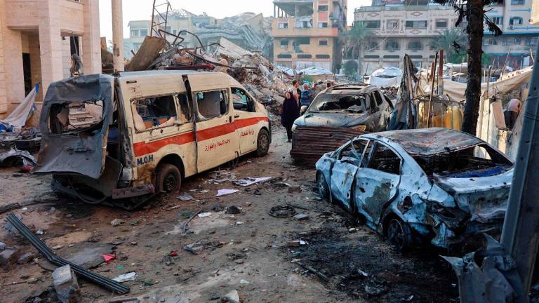 Palestinians inspect the damage, including a destroyed ambulance, around a house hit in an Israeli strike a day earlier in western Beit Lahia in the northern Gaza Strip on July 23, 2025. - Omar AL-QATTAA / AFP