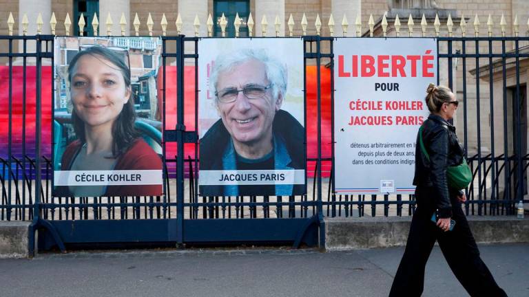 A woman walks past posters with the portraits of Cecile Kohler and Jacques Paris, two French citizens held in Iran, on the day of support rallies to mark their three-year detention and to demand their release, in front of the National Assembly in Paris, France, May 7, 2025. REUTERSpix